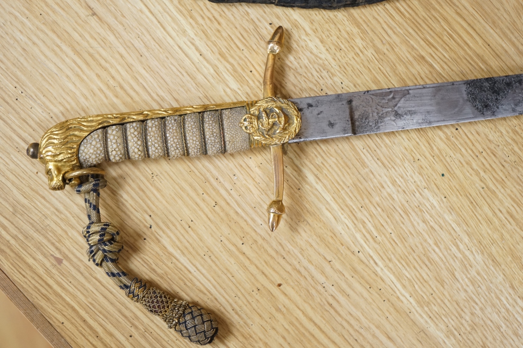 A post 1902 regulation Naval Officer’s dirk with lion’s head pommel, bullion dress knot, shark skin covered grip, in its leather scabbard, the gilt locket engraved with owners initials; CHCO’ R, the blade etched with cro